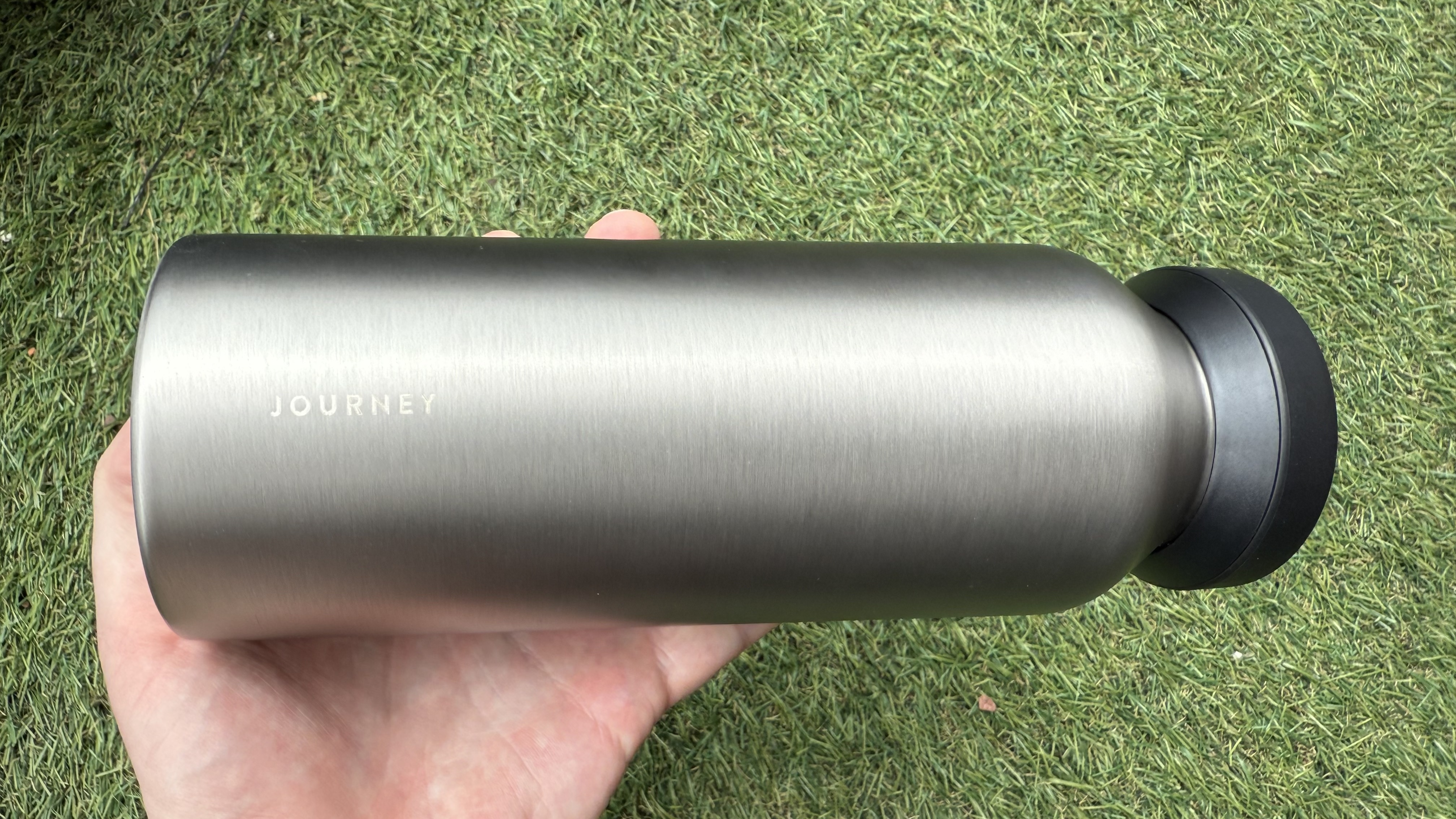 The Journey Reevus water bottle on a faux-grass surface