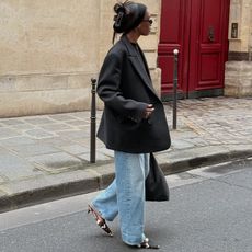 liv wears oversized blazer, jeans, and cow print pointed heels while posing on street in front of a red door