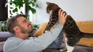 Man holding cat up and smiling