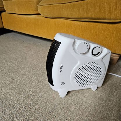 white Abode fan heater stood vertically next to yellow sofa