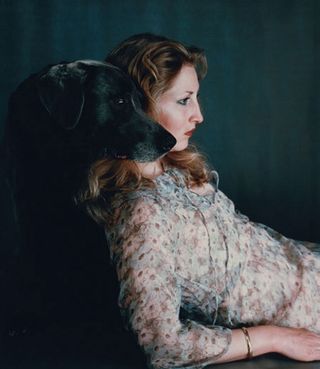 Black dog resting it's head on a woman's shoulder