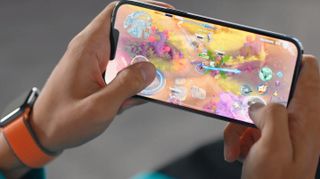 Spil afspillet på en iPhone 13 Pro, der holdes i to hænder
