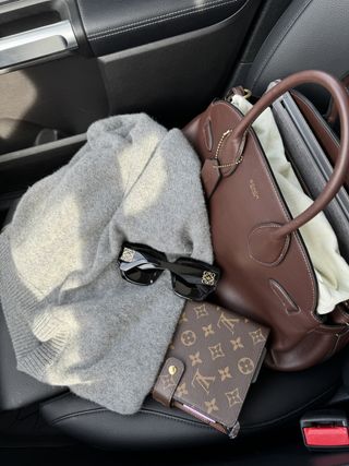 A Coach Empire Carryall bag sitting on a car seat.