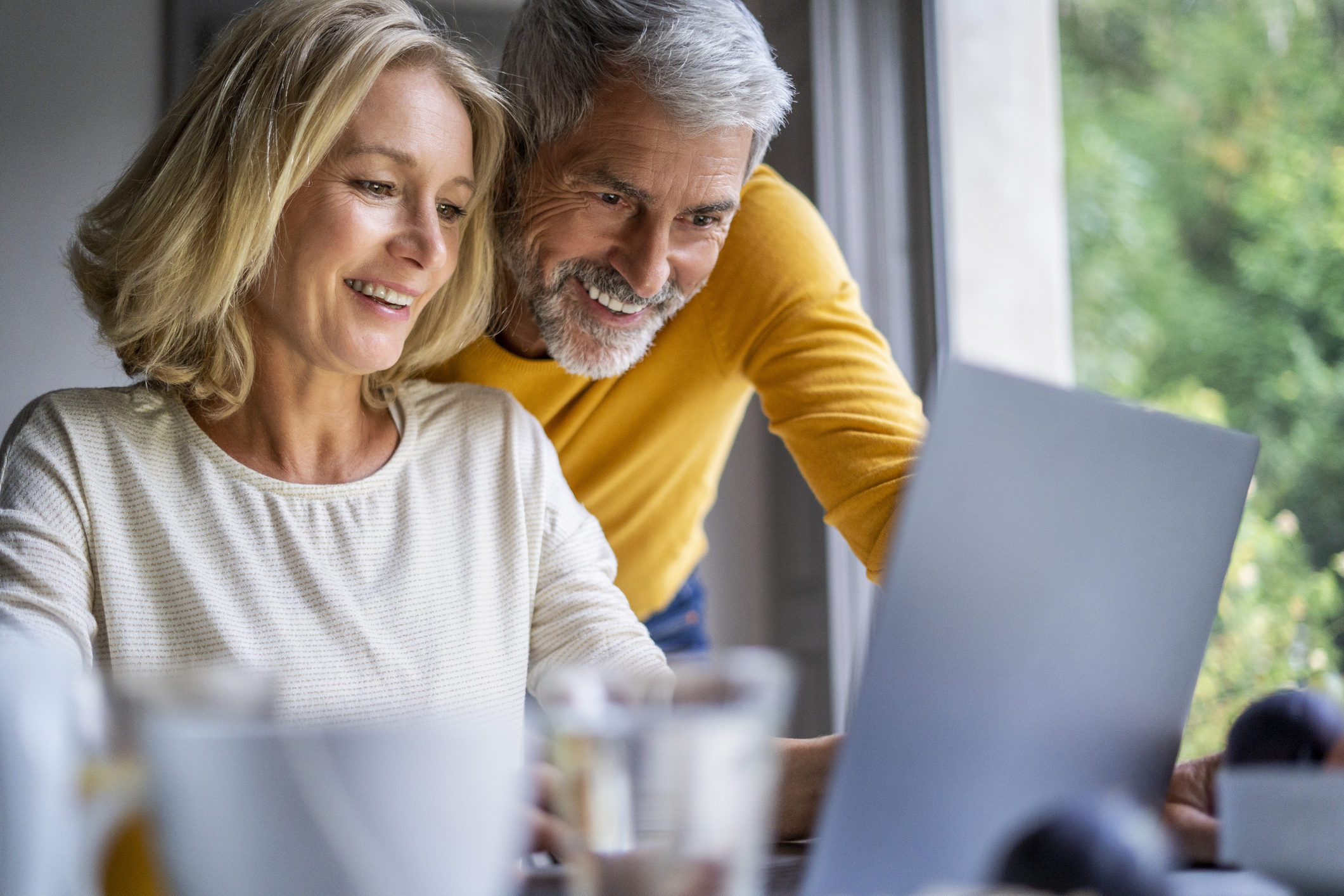 Smiling mature couple using laptop at table at home