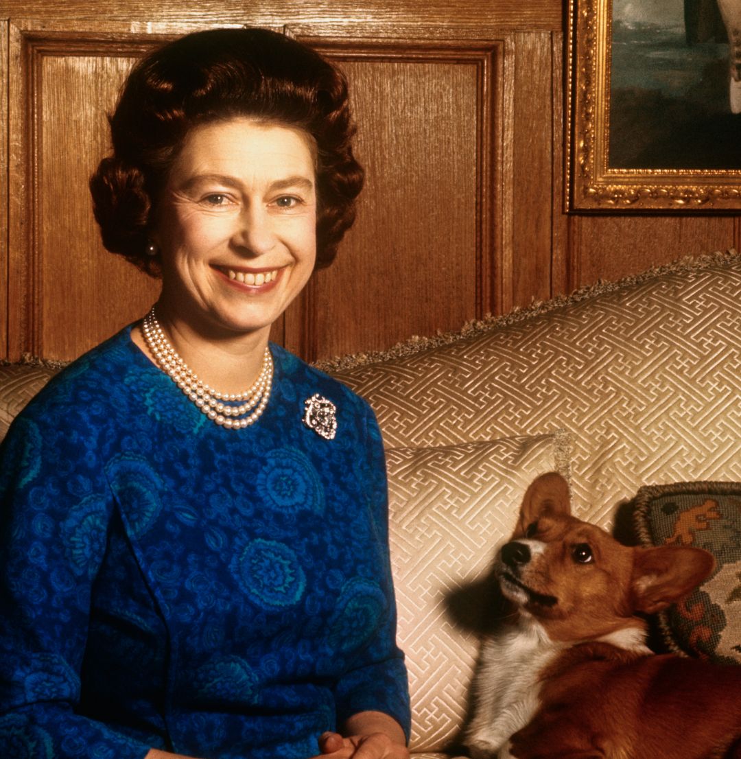 Queen Elizabeth sitting on a sofa with a corgi