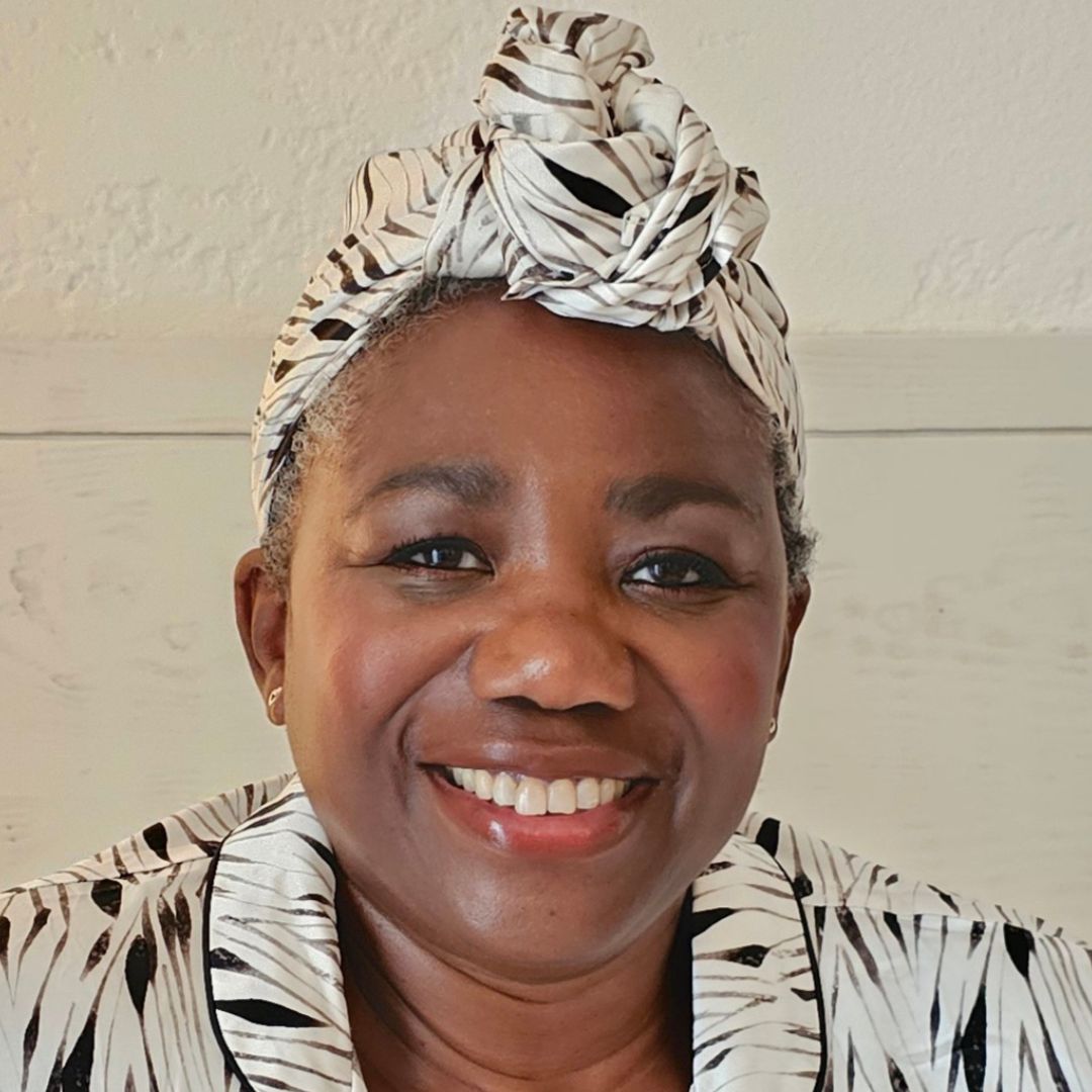 Joyce Connor pictured wearing the x silk hair wrap, tied around her hair and smiling to the camera