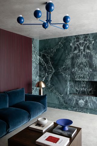 marble wall in a living room with blue sofa and gold lamp