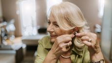 Woman putting in hearing aid - Hearing aids could help prevent dementia and help people live longer