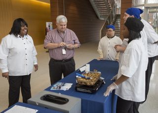 New Horizons Culinary Instructor Tonya Ward, left, and HUNCH founder and Program Manager Stacy Hale talk to the team that made the baked penne about their dish, on Feb. 16, 2016, at NASA's Langley Research Center in Virginia.