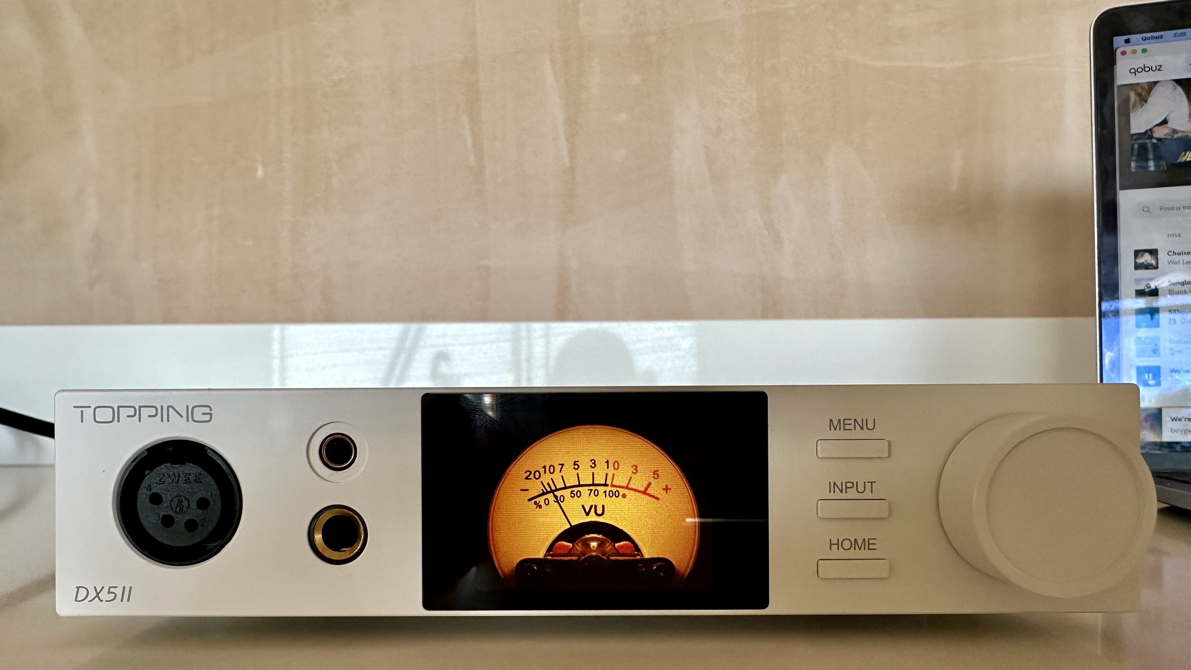 The Topping DX5 II on a light-wood table, showing the VU meter, ports and just-seen remote