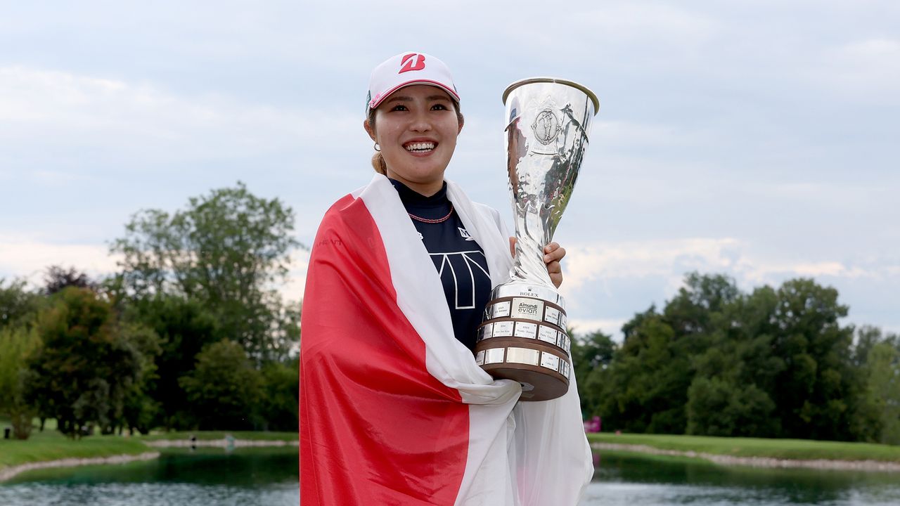 Ayaka Furue holds the 2024 Evian Championship trophy with a Japan flag draped around her