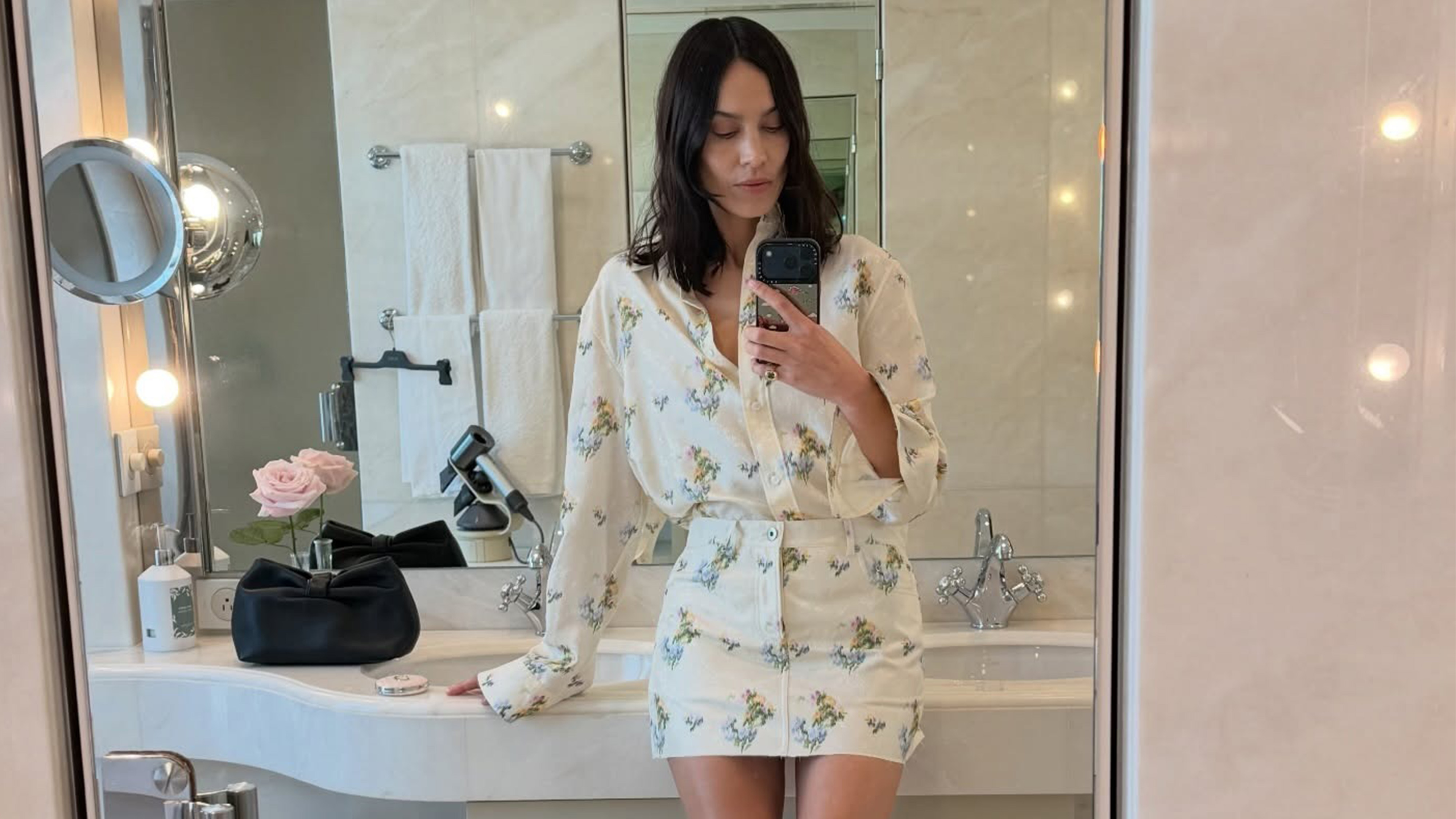 Alexa Chung wearing a Dior floral shirt and matching miniskirt in a bathroom selfie. 