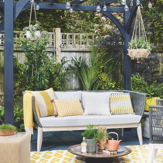 pergola with bistro lights and hanging plants and seating area