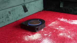 En iRobot Roomba S9+ samler støv op fra et rødt gulvtæppe