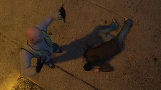 A man in a hi-vis vest standing with his hands raised while a body lies at his feet in GTA 5