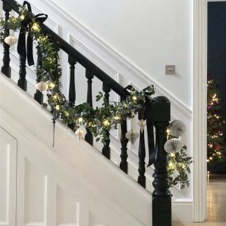 Christmas stair decor garland and fairy lights in white hallway