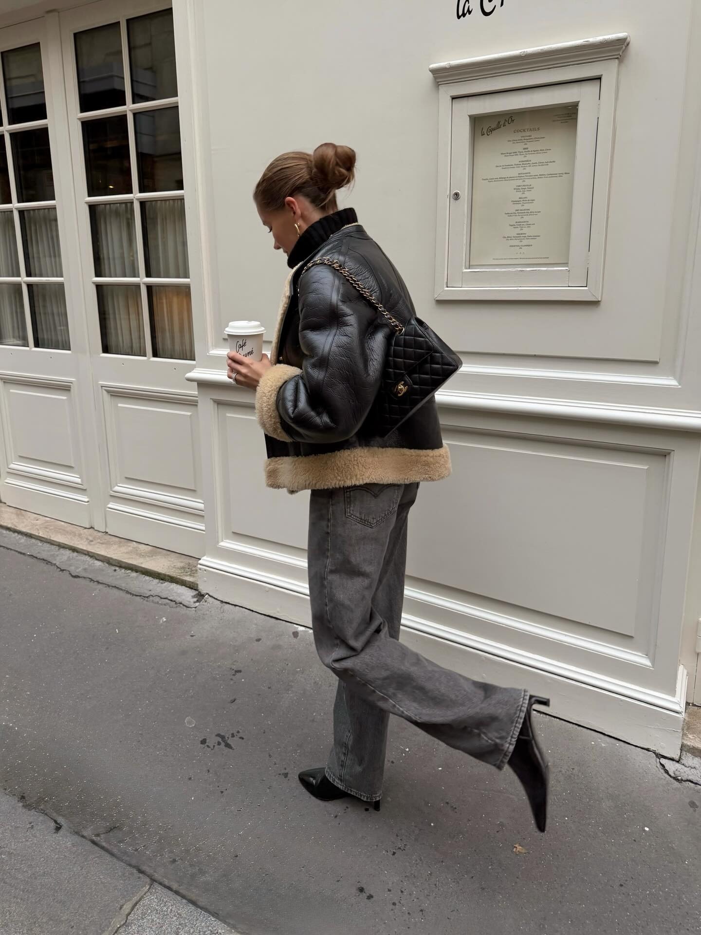 French woman wearing leather motto jacket, grey denim, and black leather ankle boots on the streets of Paris.
