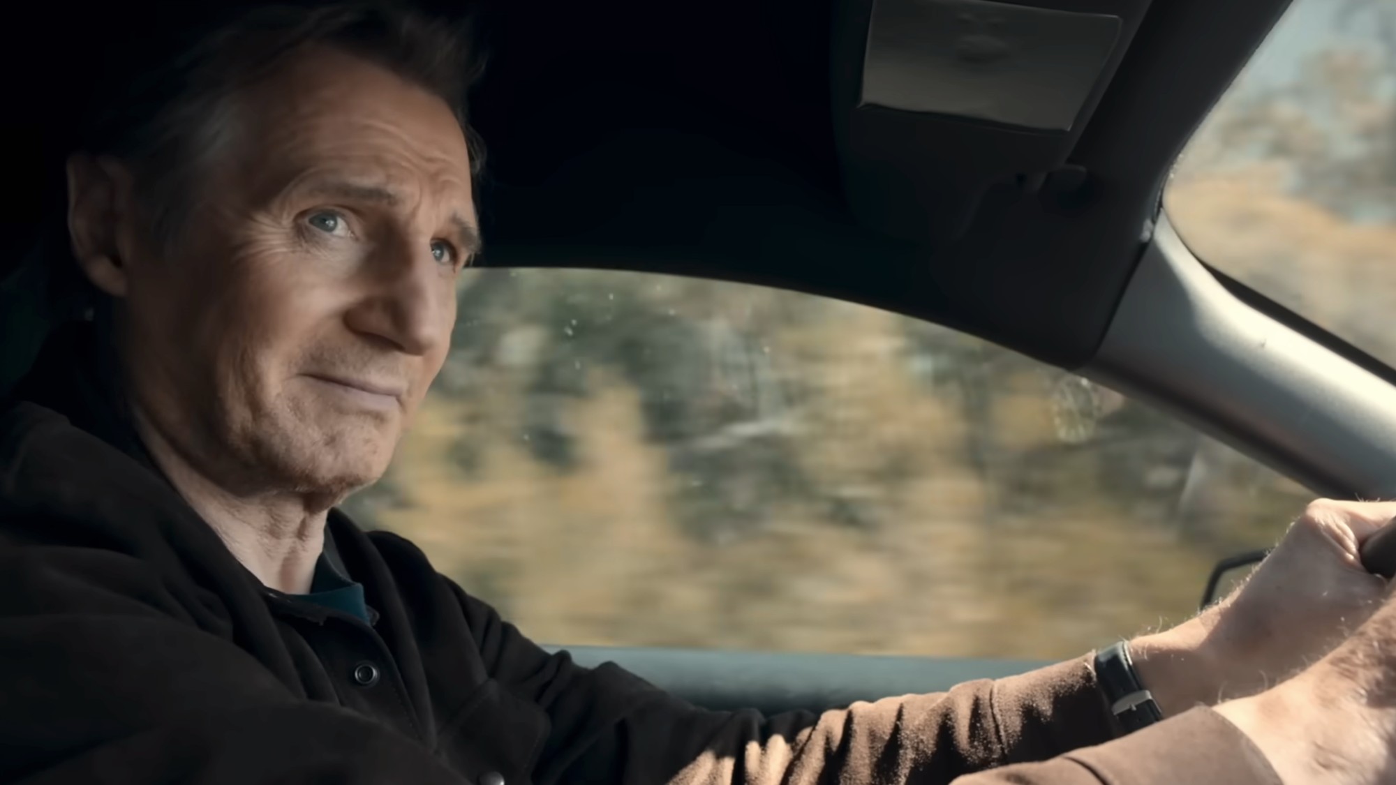 A close up of Liam Neeson driving a and looking to his left in The Mongoose.