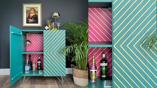 pink and teal coloured cabinet with one door open and gold striped detailing