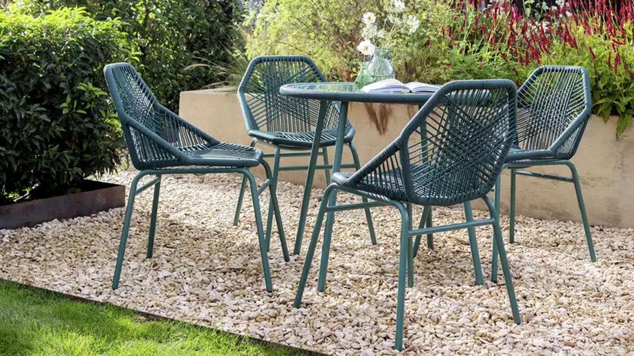 Dark green Habitat Hector 4 seater rattan effect patio set on gravel in garden