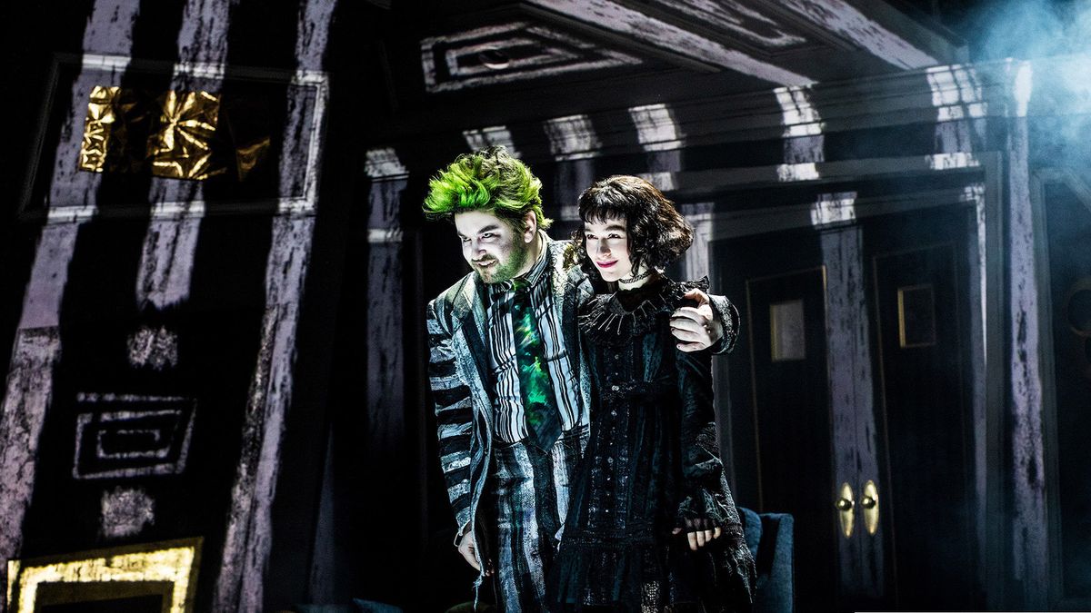 Stars Alex Brightman (left) and Sophia Anne Caruso stand illuminated by a mixture of traditional stage lighting and laser projection.