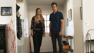 Sheila and Joel looking at dead body on their living room floor next to a bloody wall in Santa Clarita Diet