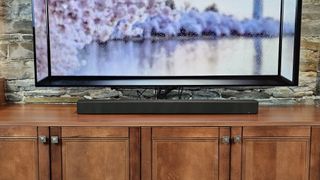 The Sony Bravia 7 soundbar pictured underneath a TV on a wooden cabinet
