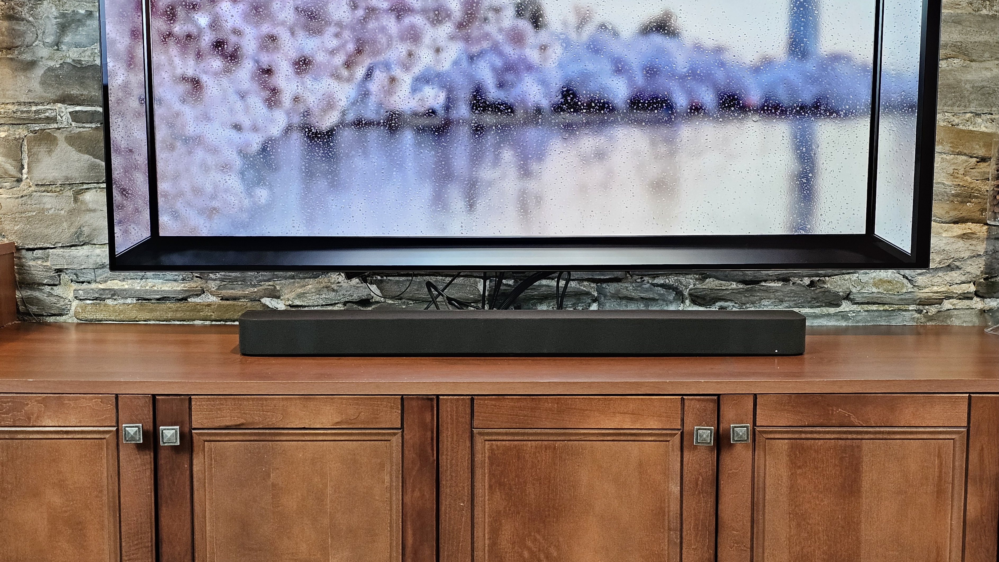 The Sony Bravia 7 soundbar pictured underneath a TV on a wooden cabinet