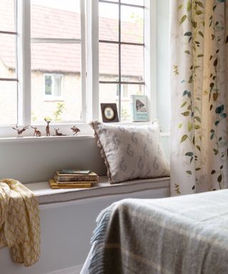 window seat in a cottage bedroom with cushions and books