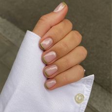 A close up of a French manicure with green French tips