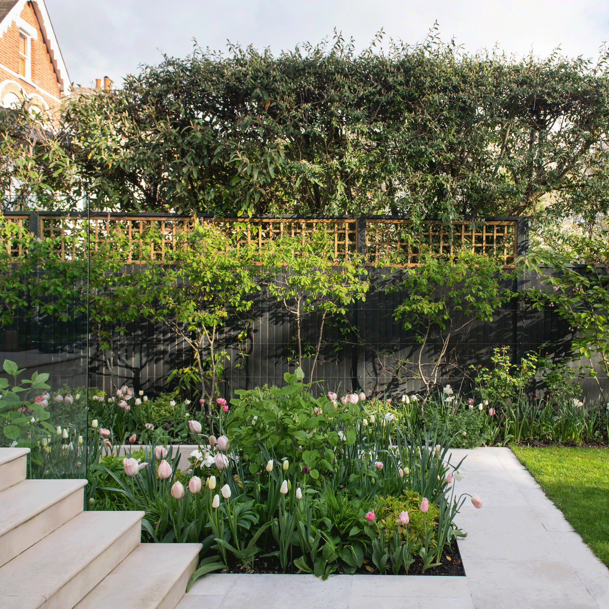 a garden with tulip-packed flowerbeds beside steps and fencing