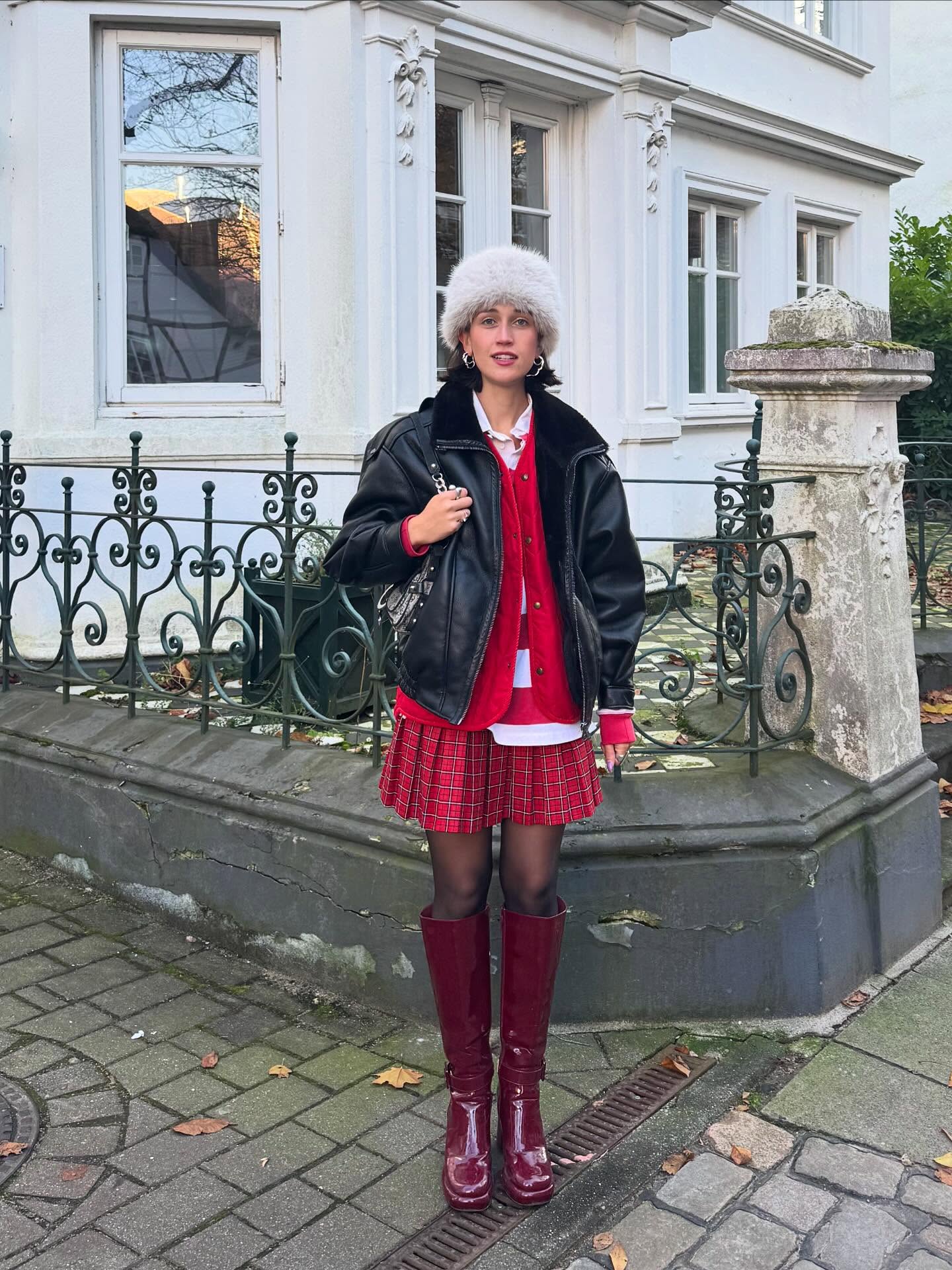 How to Wear a Kilt: Leonie Charlotte wears a leather jacket, red cardigan, red tartan kilt and red leather boots