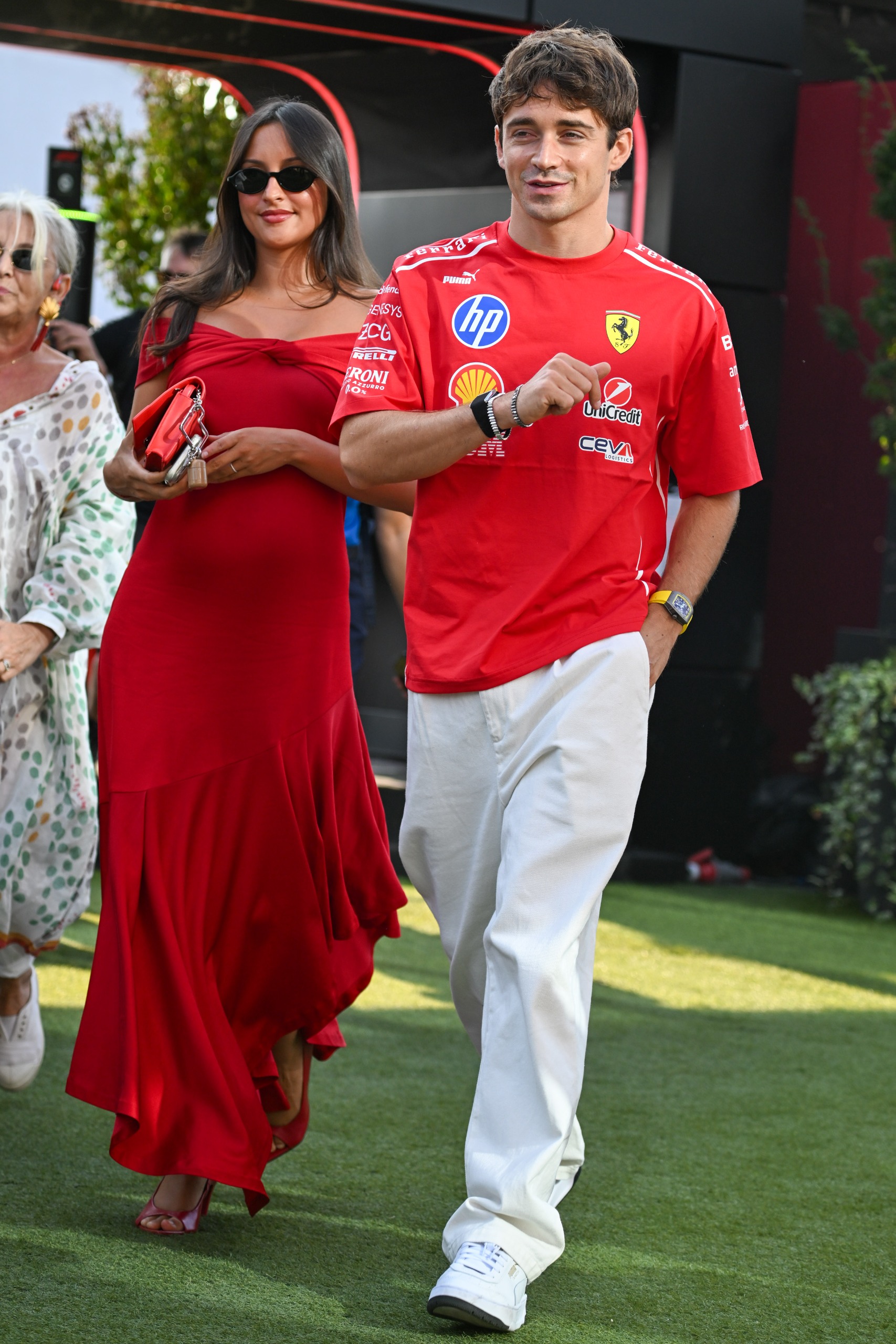 Alexandra Leclerc wearing a red Ferrari dress, she has long brown hair and is pregnant while wearing sunglasses