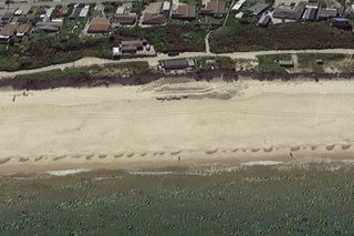 Hemsby beach seen from above and showing a house falling into the cliff below