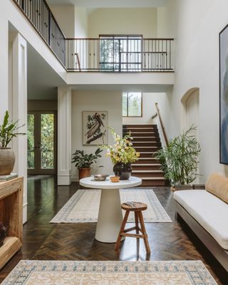 Rugs in a large entryway with a mezzanine, neutral tones and rugs