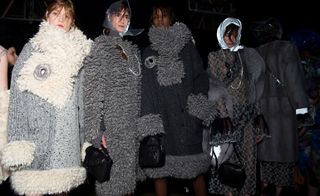 Female models lining up wearing large dark winter coats