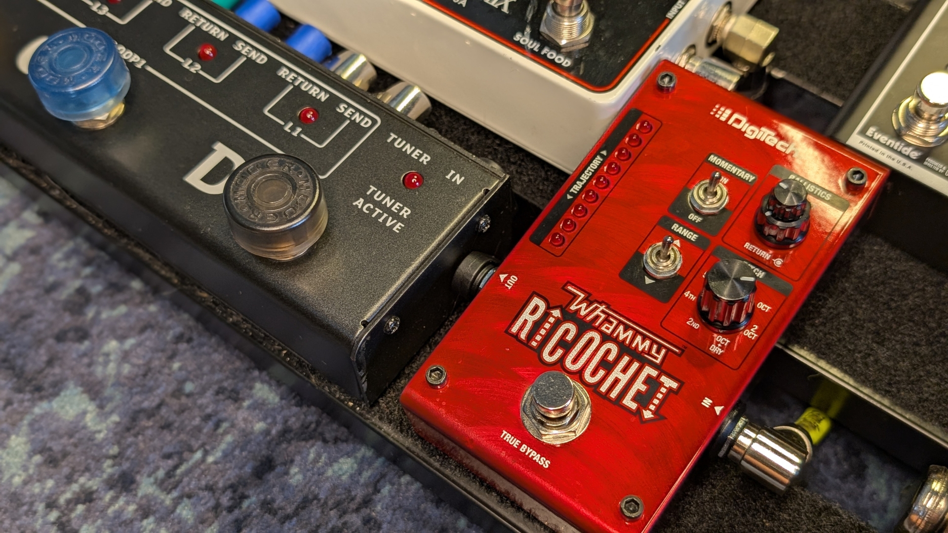 A closeup of a pedalboard with guitar pedals, pedal switcher, and patch cables
