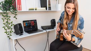 Woman plays guitar while running AmpliTube 5 Max