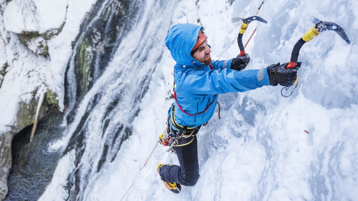 A man ice climbing using two axes