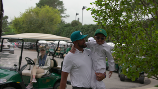 Tony Finau holding his youngest son at a golf tournament