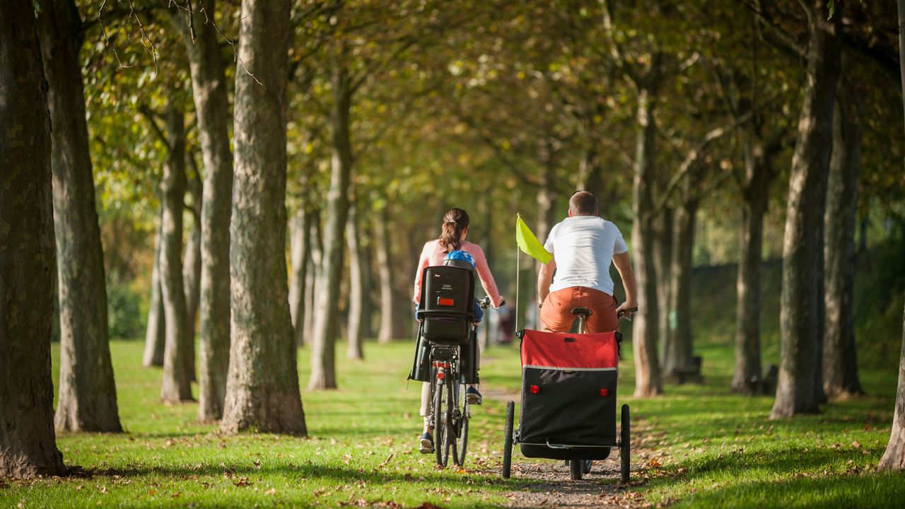 Couple ride away from camera with child in trailer