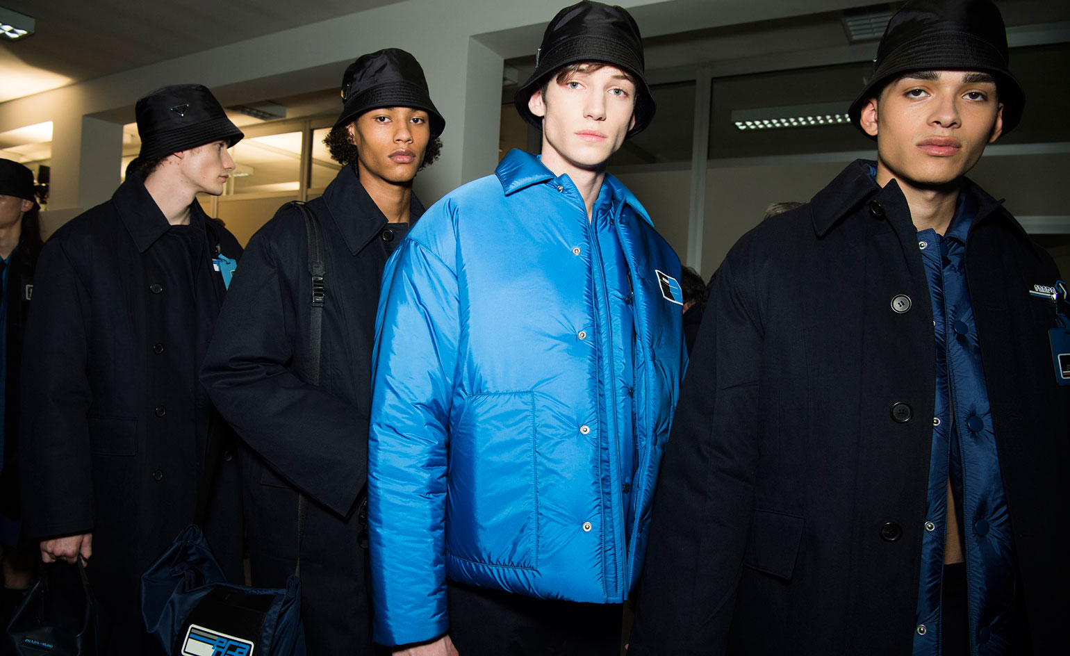 Four young men wearing jackets and hats.
