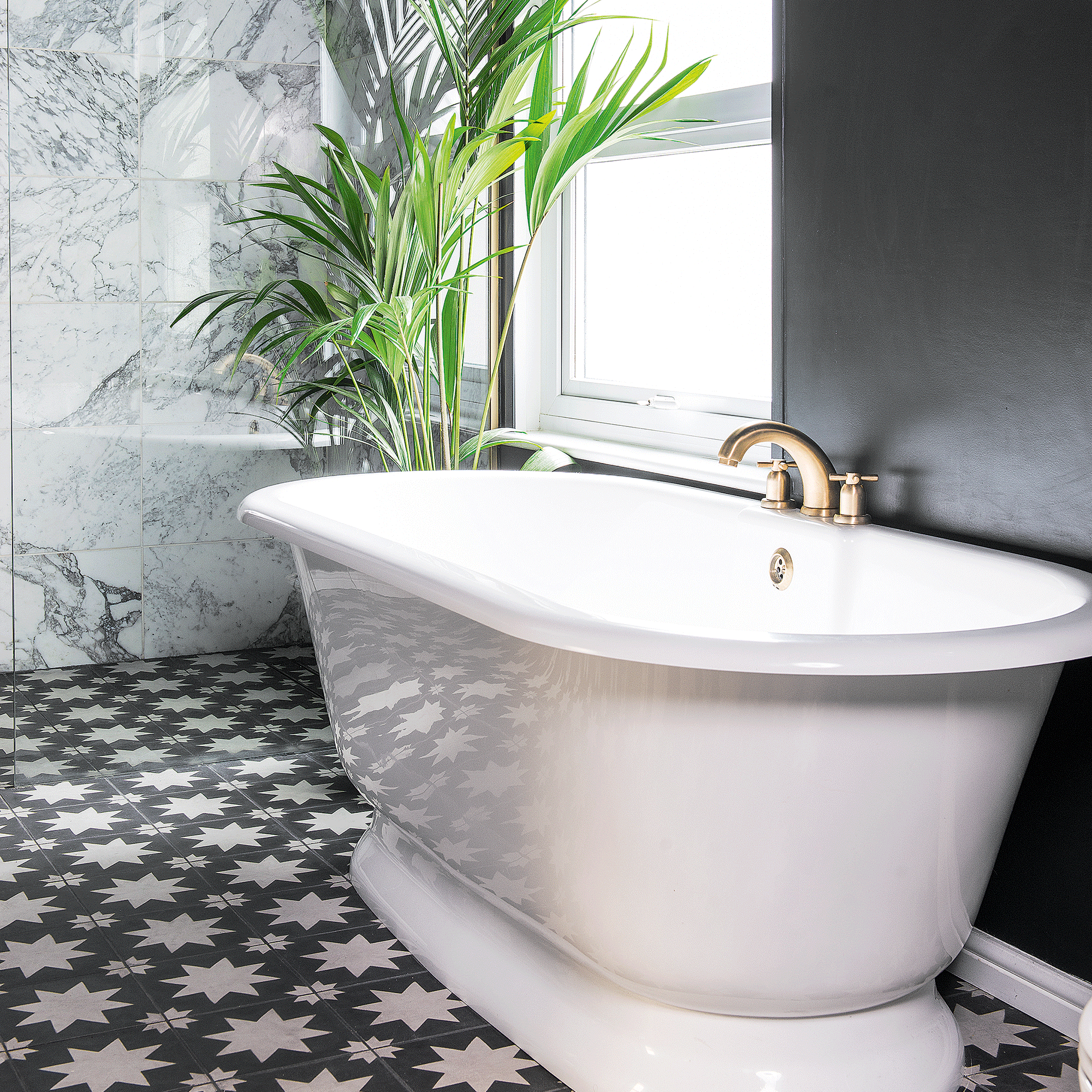 White freestanding bath with gold taps and plant