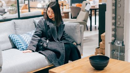 Young woman at furniture store choosing sofa - stock photo