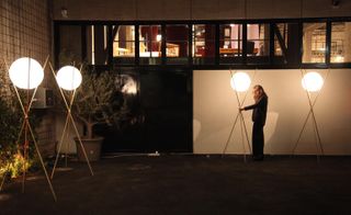 Lighting installation being set up outside, It consists of round lights balancing between three crossed rounded pipes.