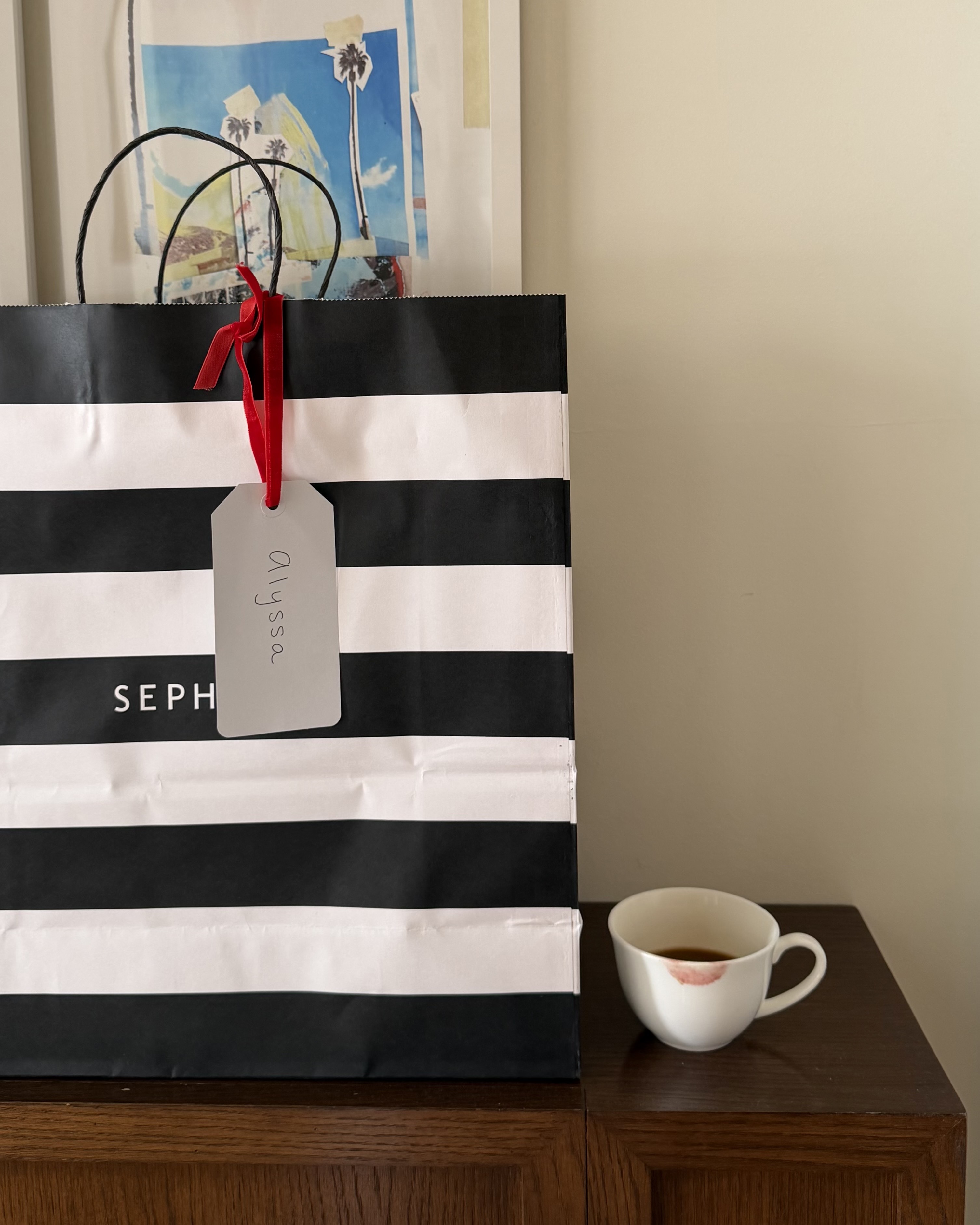 A Sephora bag next to a coffee cup with a lipstick stain.