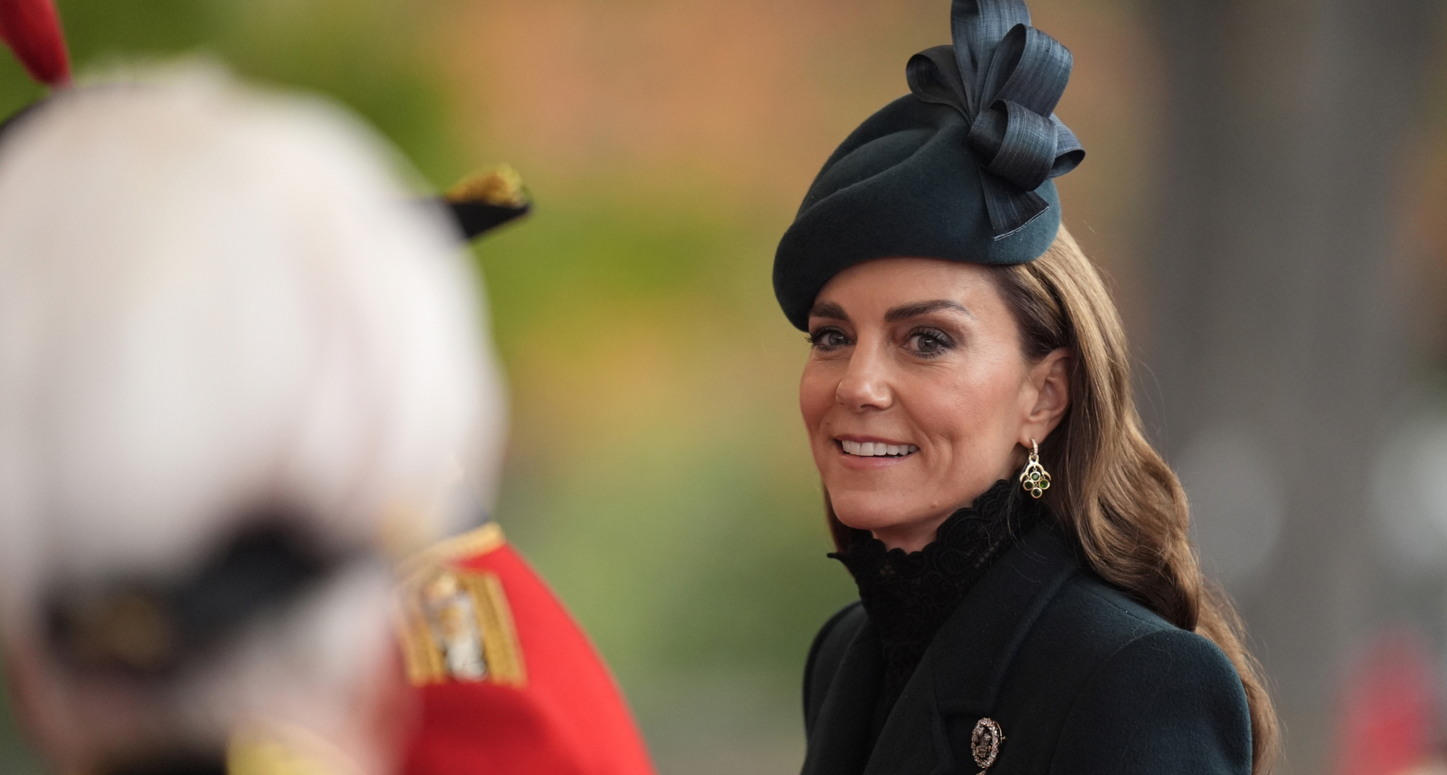 Princess Kate wearing a green hat and coat and smiling