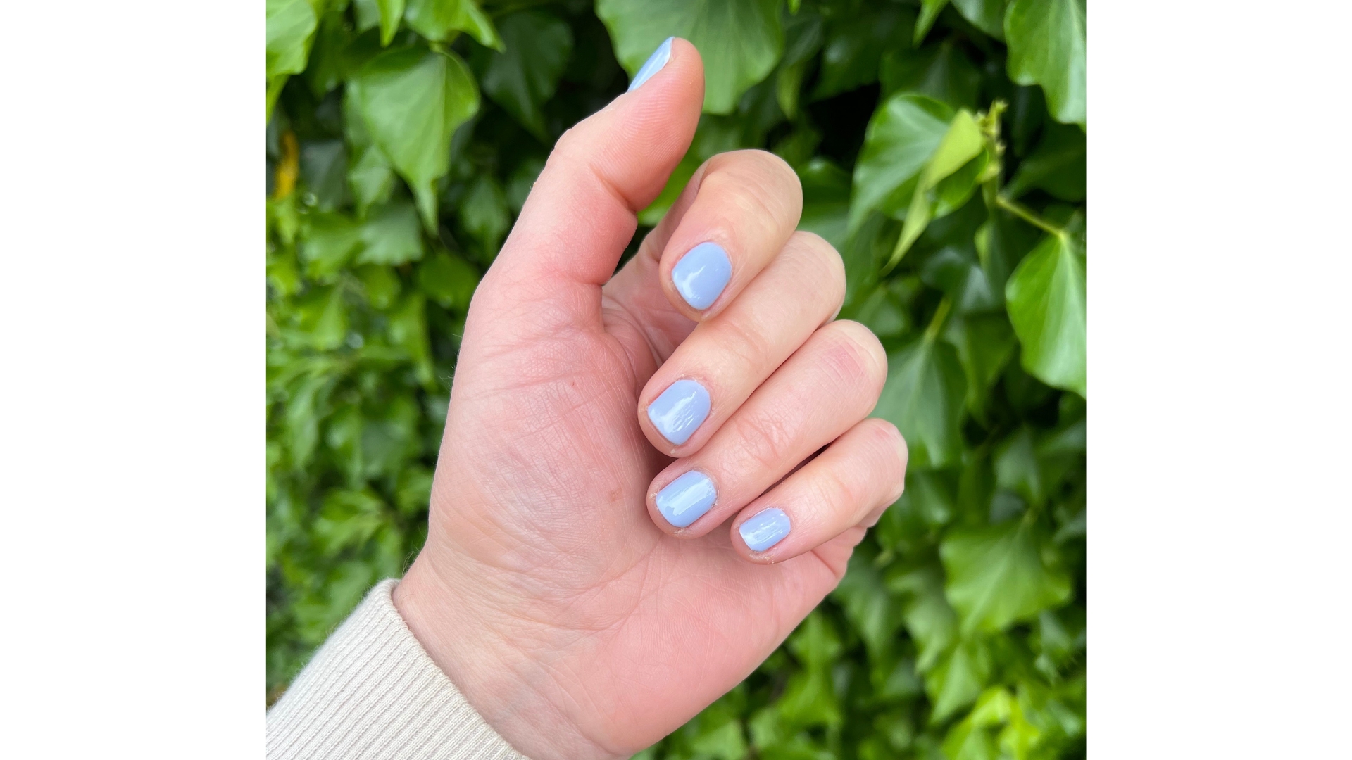 A picture of Beauty Editor, Fiona McKim's lavender nails, taken in front of a green, leafy background