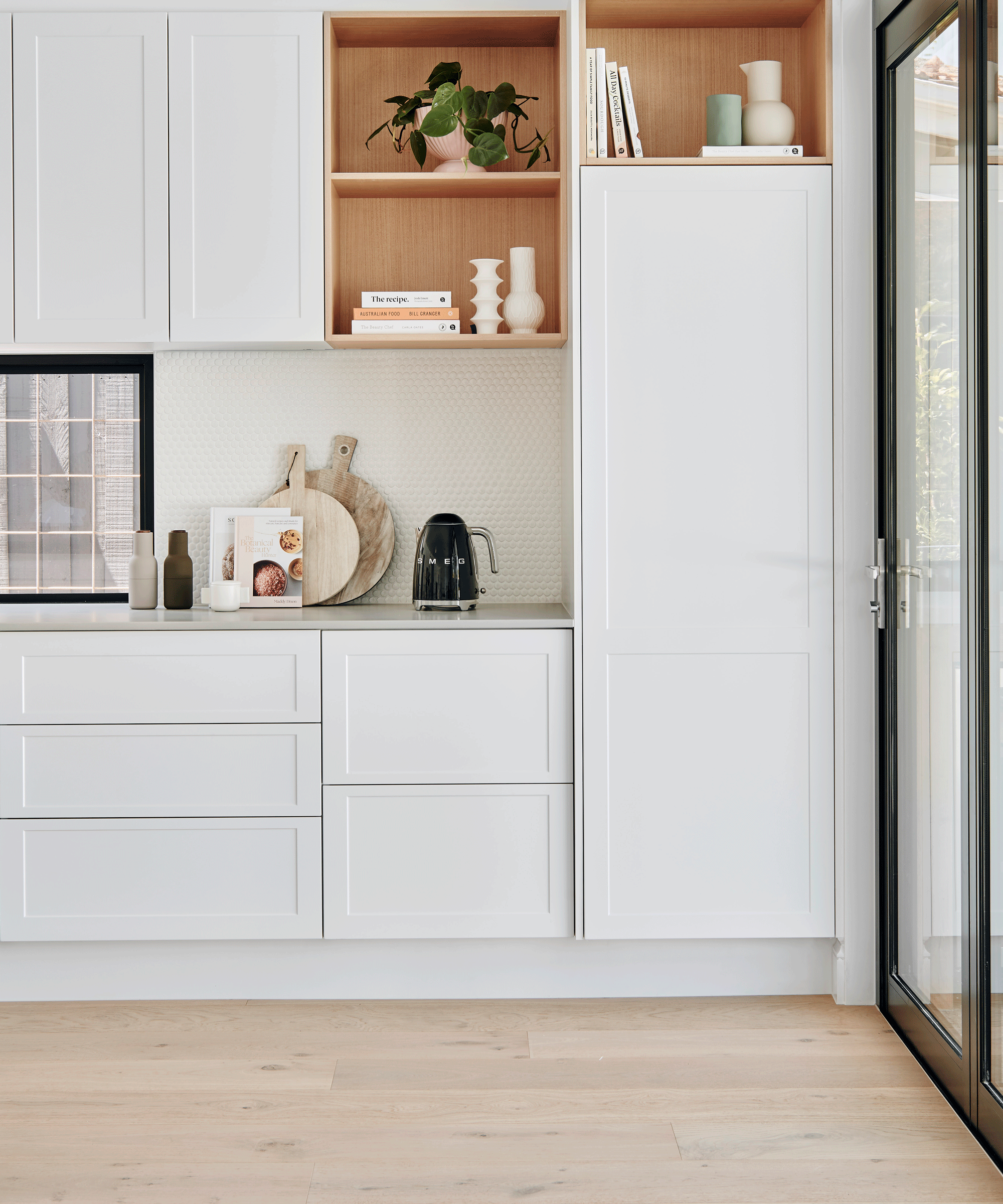 a modern white kitchen with shelves and wooden floors