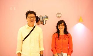 A man and woman smiling and posing for a picture against a pink wall background